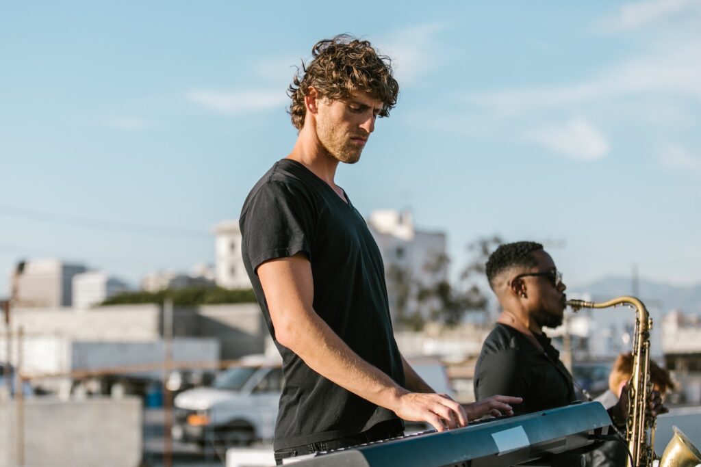 A Man in Black T-shirt Playing the Keyboard Beside a Man Playing the Saxophone